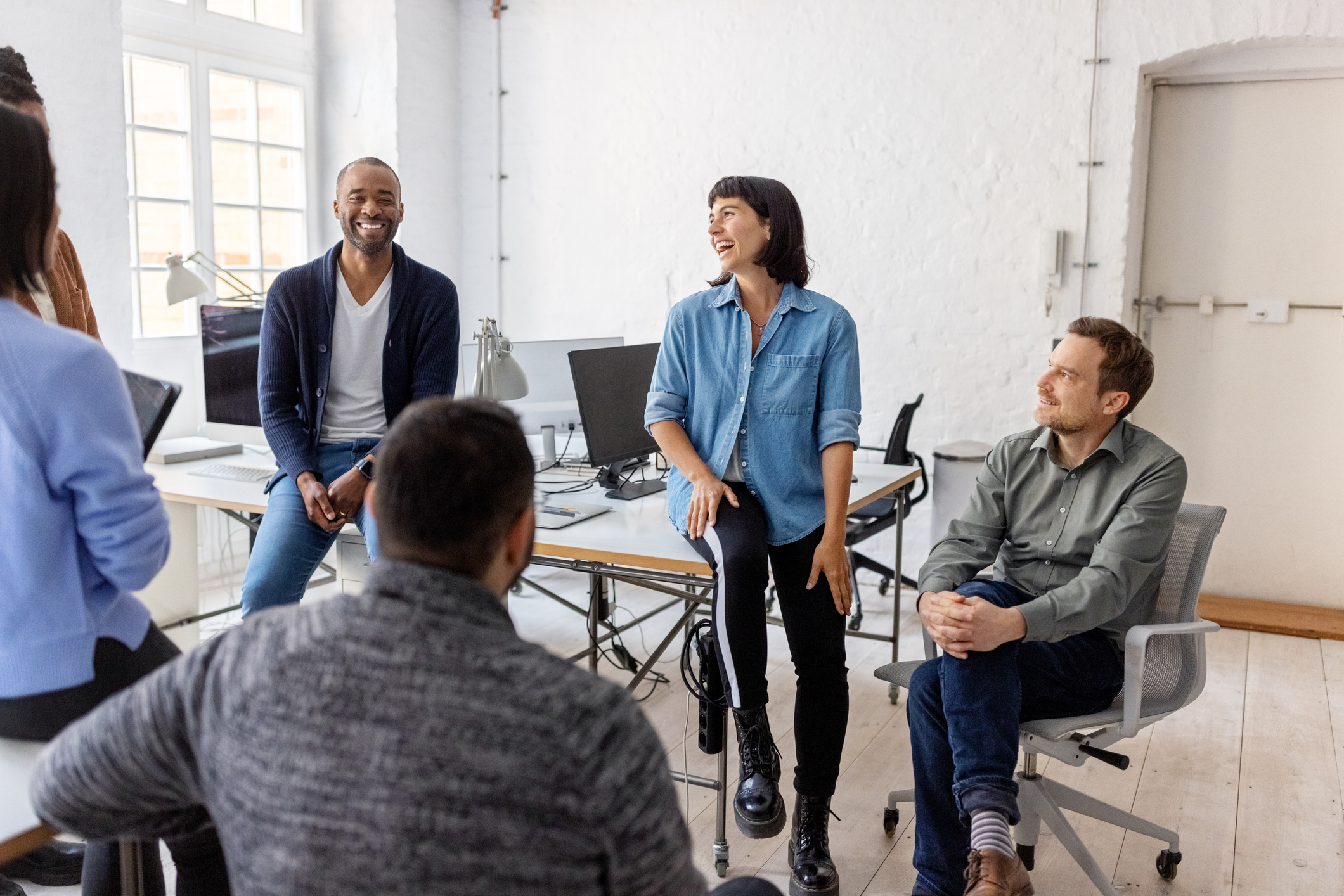 three colleagues talking and smiling in an office setting 