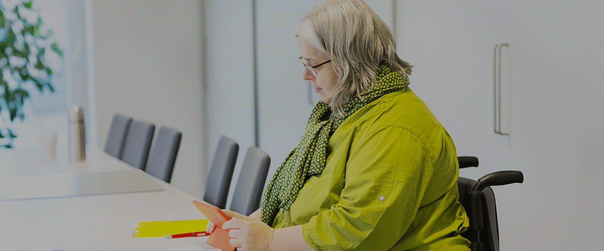 consultant lady in yellow sat at a table alone reading from her tablet